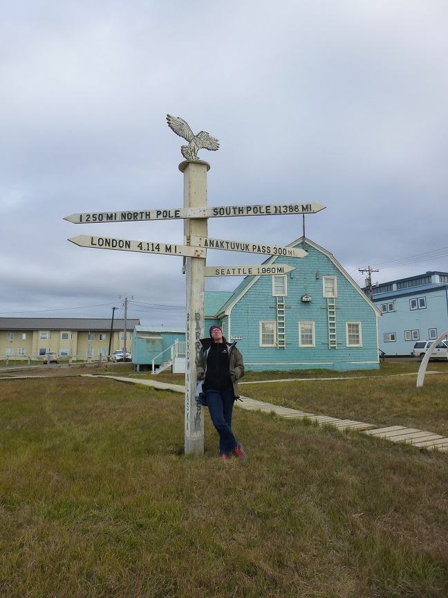 Me at signpost in Barrow, showing distance to North and South pole.